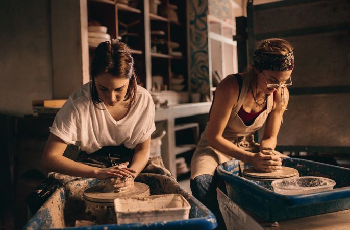 Two women at a pottery workshop making clay pots in studio