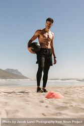 Athletic man standing with weighted ball at a beach 4dJwE0