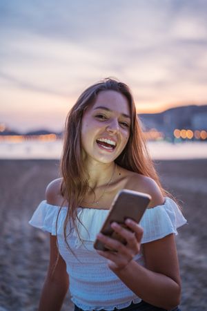 Cheerful young woman using smartphone on resort