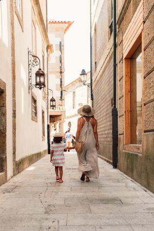 Mother and daughter walking in street along ancient building