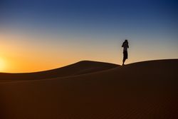 Anonymous traveler in desert during sunset