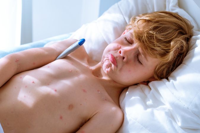 Upset ill boy measuring temperature