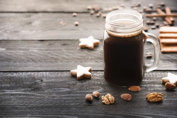 Mason jar with coffee and cookies on rustic wooden table