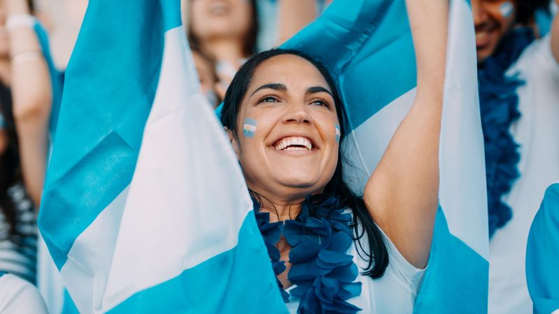 Woman with garland and Argentina flags cheering from stadium fan zone