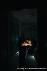 Young man studying with desk lamp in dark room 4A8e65