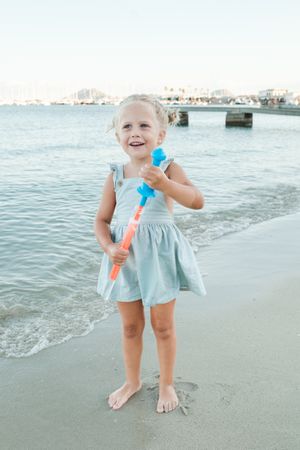 Cute little holding bottle of soap bubbles at beach
