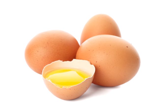 Chicken eggs and half yolk isolated on light background
