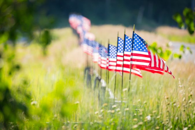 Row of American Flags  Waving in the Wind Along A Fence.