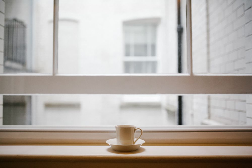Ceramic mug on saucer beside glass window