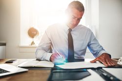 Man in business attire signing documents in his sunny office