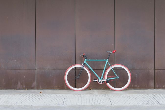 Red and green bicycle parked against a brown wall