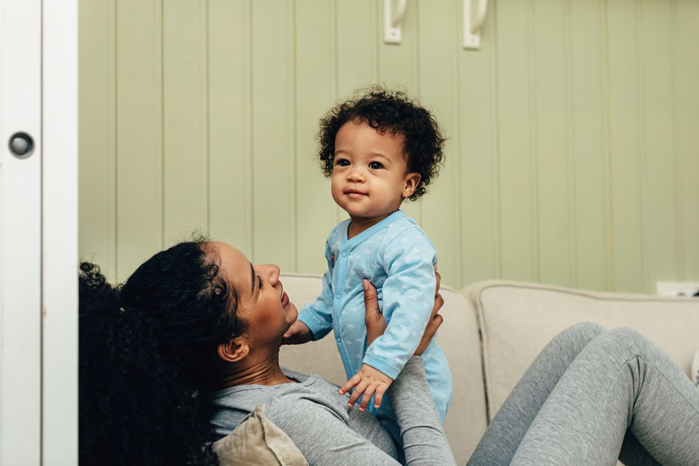 Mother on sofa smiling at her happy toddler
