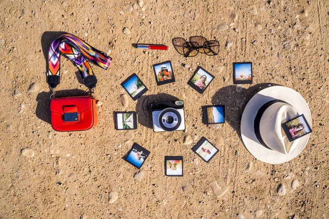 Stylish accessories and instant photos on sandy ground