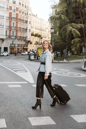 Cheerful female tourist crossing street
