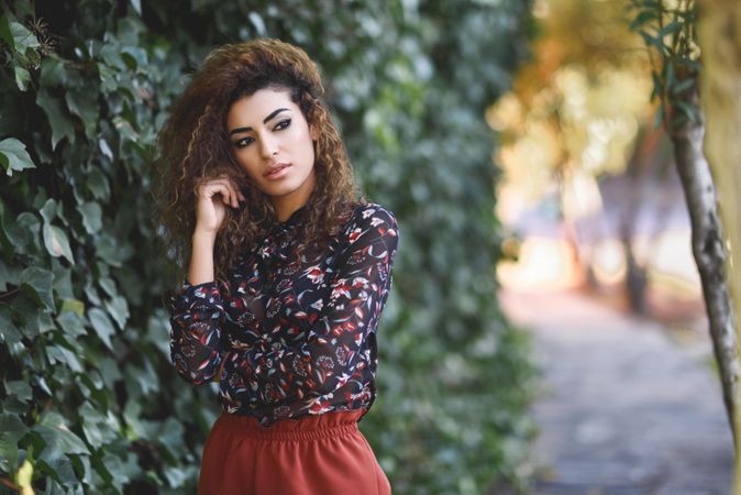 Serious Arab woman wearing casual clothes in the street lined with greenery