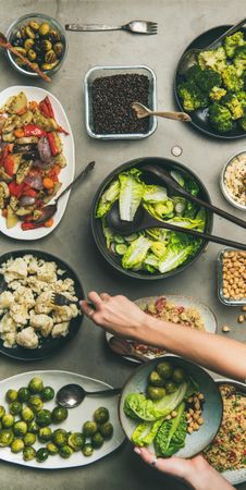 Top view of woman’s hands taking cauliflower from table of healthy vegan food