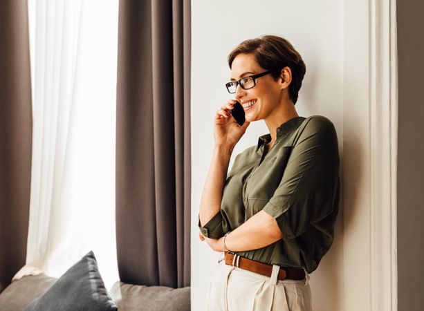 Smiling woman leaning on wall taking a phone call