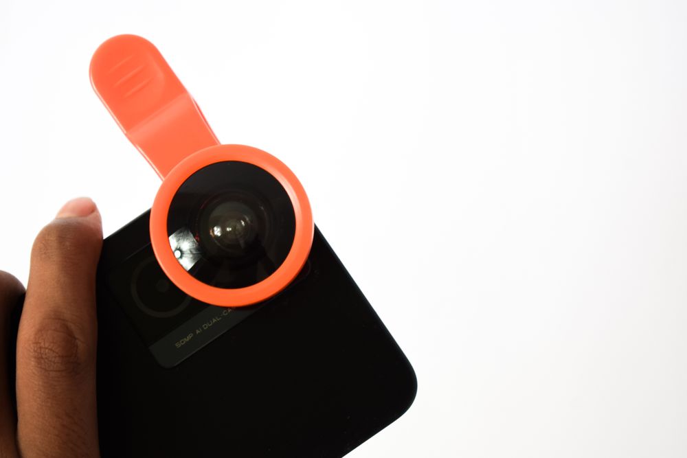 Hand holding smartphone with additional lens