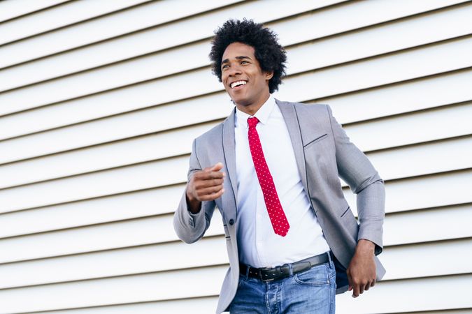 Man in jeans and dress shirt smiling and walking outside