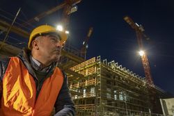 Construction worker beside a building under construction at night