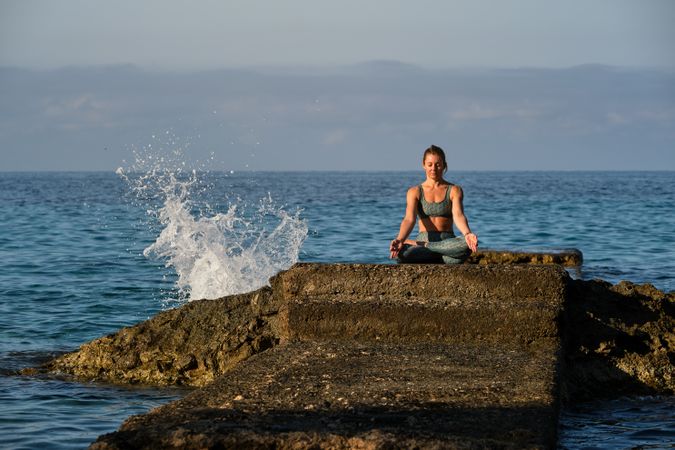 Woman in sportswear sitting on stone and meditating