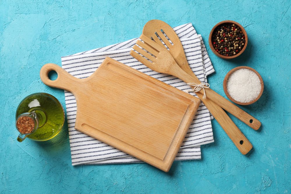 Kitchen cutlery, oil and spices on blue background, top view