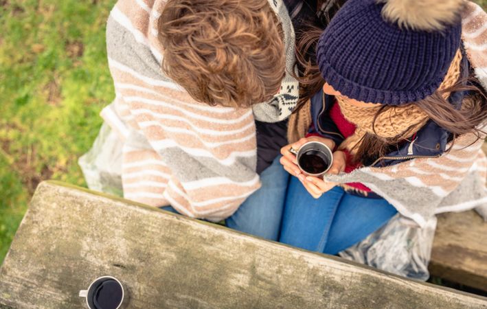 Top view of couple drinking coffee on park bench