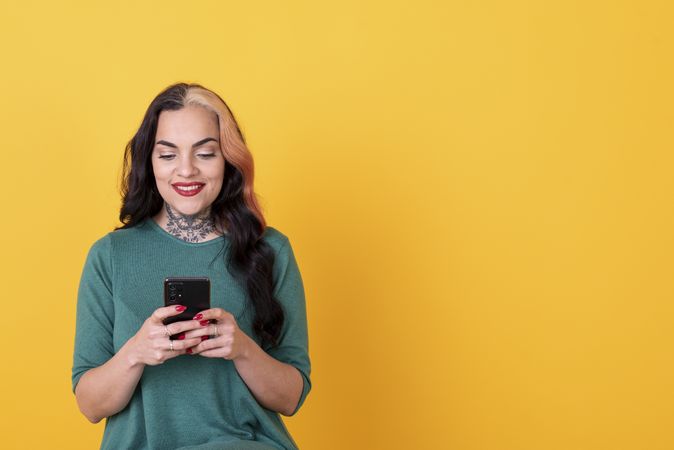 Portrait of a woman using smart phone over yellow background.  Copy space