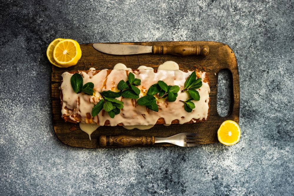 Top view of freshly baked lemon cake dessert with mint garnish on wooden board and copy space