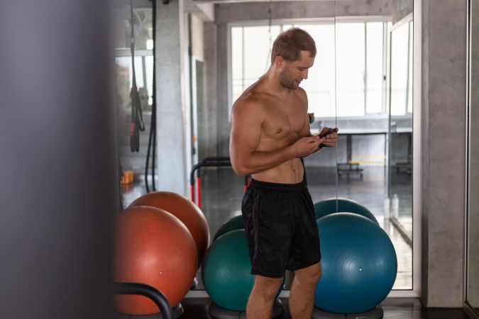 Healthy man using mobile phone at the gym