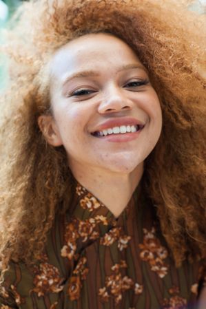 Close up portrait of a young woman with an afro smiling and looking into the camera