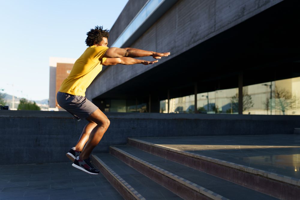 Man doing jump squats on stairs outside