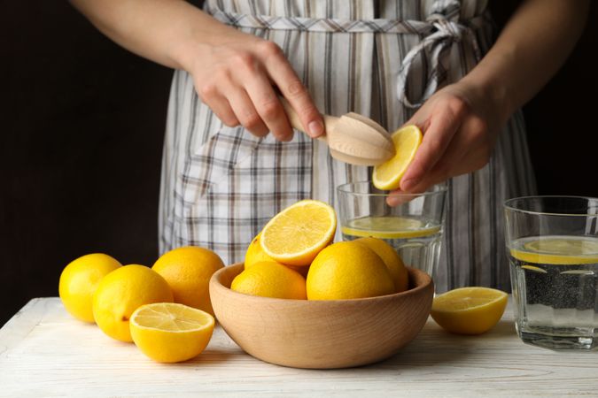 Woman squeezes juice. Composition with lemons. Ripe fruit