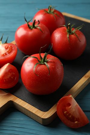 Fresh tomatoes on board on wooden table. Ripe vegetable