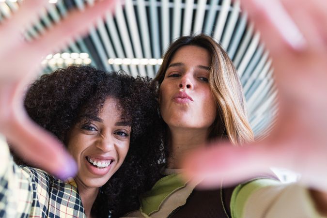 Smiling multiracial girlfriends having fun while showing photo gesture