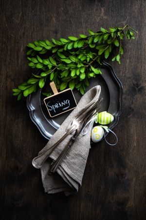 Spring table setting of dark plate and branch with green eggs