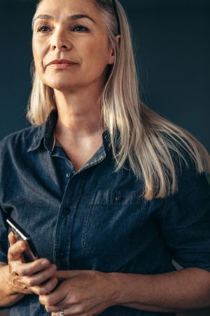 Portrait of confident woman holding phone looking away