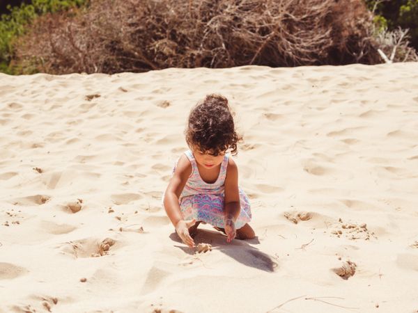 Cute little girl playing with sand at beach