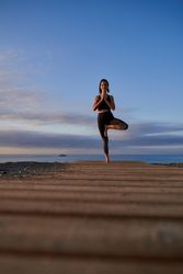 Woman practicing Tree pose on shore