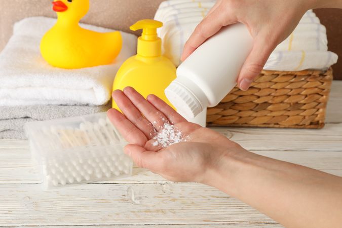 Mom applying talc powder from plastic tube. Baby hygiene
