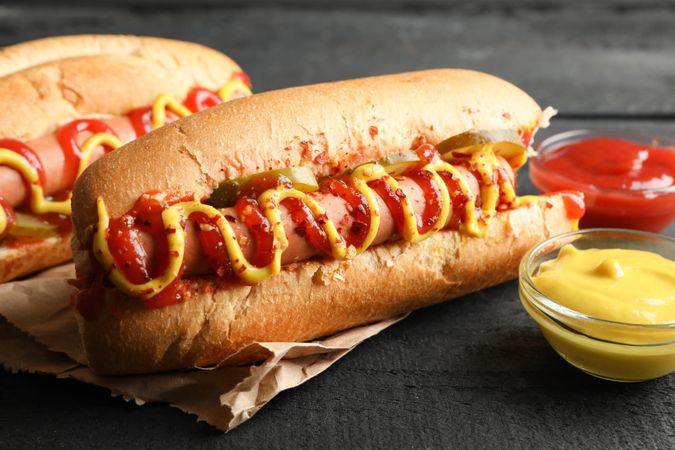 Tasty hot dogs and sauces on wooden background