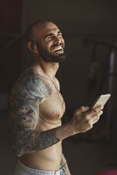 Laughing athlete with smartphone in gym