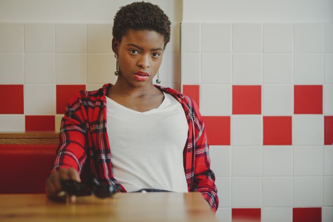 Stylish Black woman sitting at table in cafe