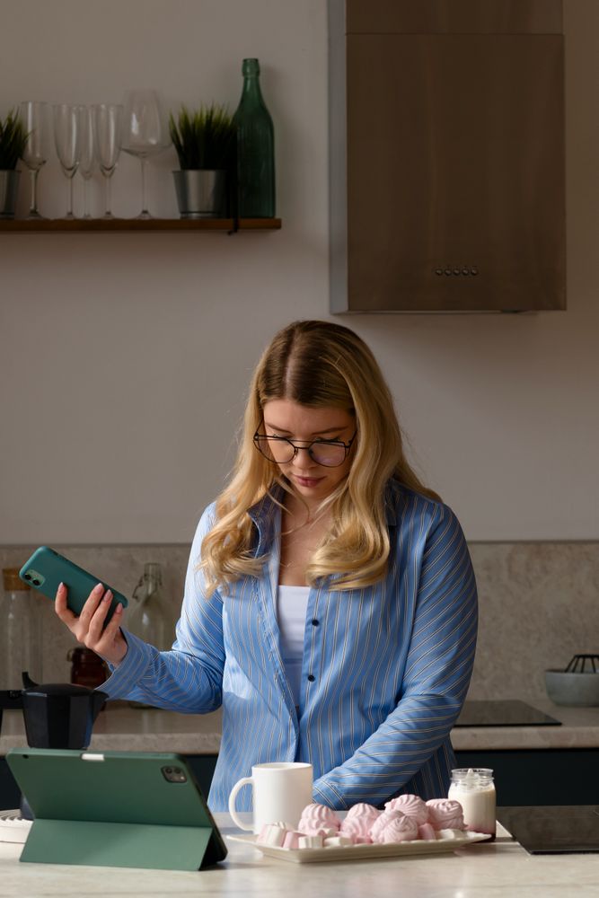 Woman using phone in kitchen with coffee