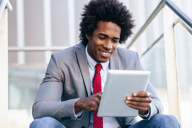 Smiling man sitting on stairs with digital tablet