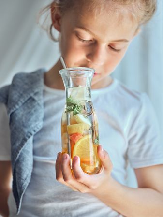 Boy looking down and holding glass bottle of lemonade