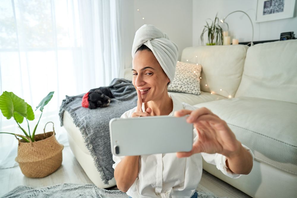 Cheerful woman demonstrating shh sign while taking on video call