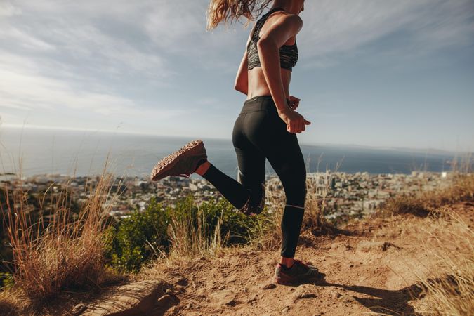 Young woman jogging on rocky path on hill