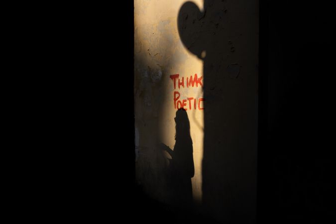 Shadow of woman walking near street grafitti