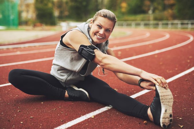 Woman stretching her legs on athletic track